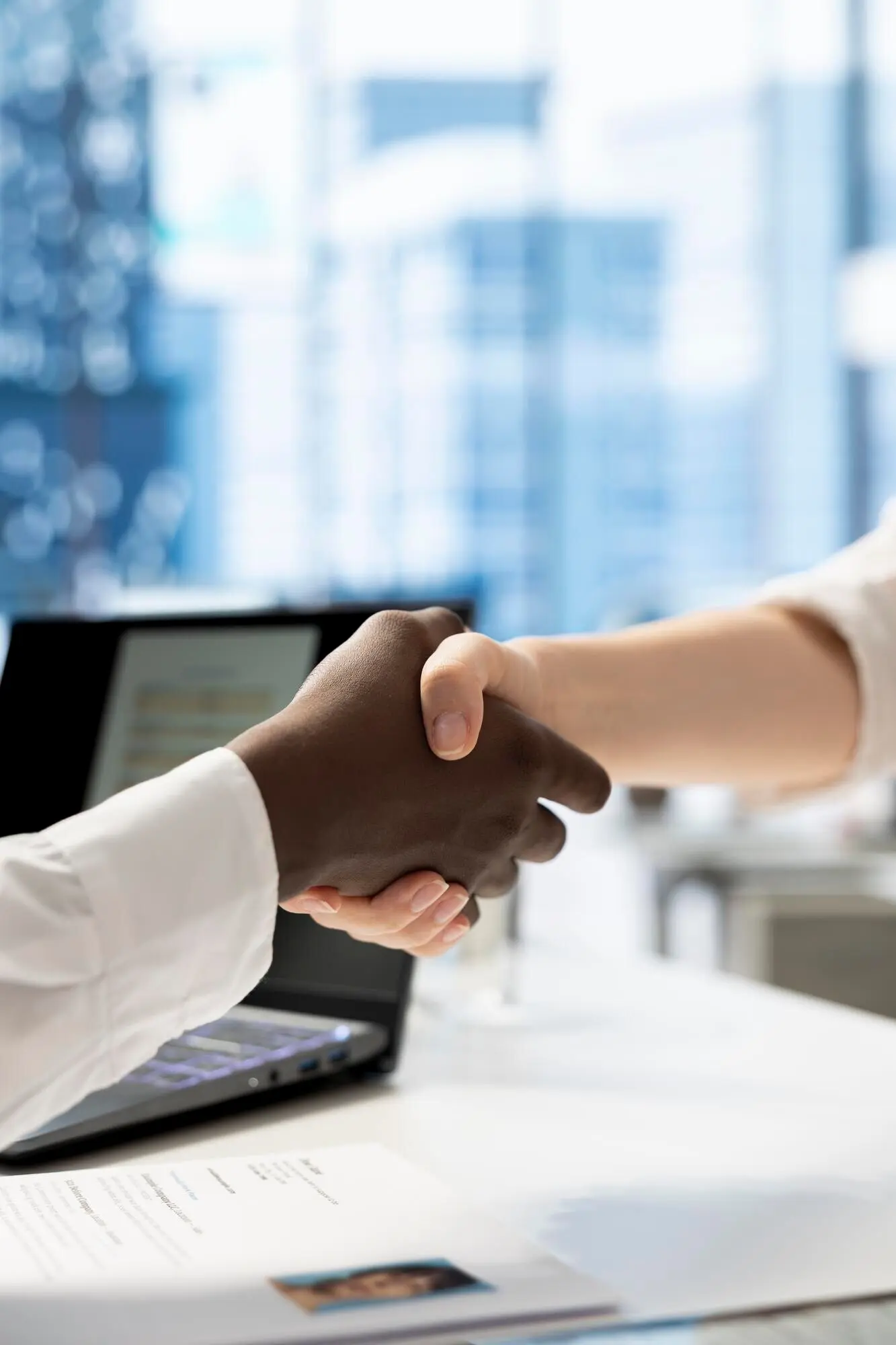 Крупный план рекрутера в офисе, приветствующего соискателя рукопожатием.